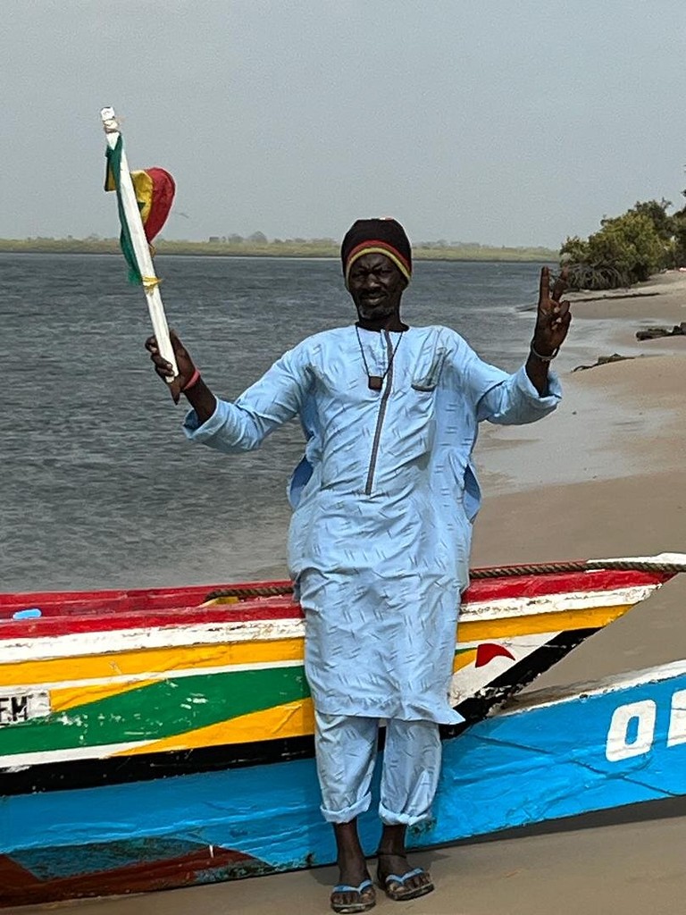 Accueil sur la plage, drapeau du Sénégal à la main