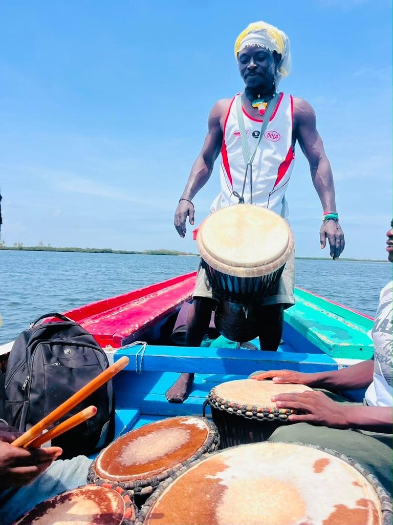 Le joueur de djembé debout à la proue de la pirogue