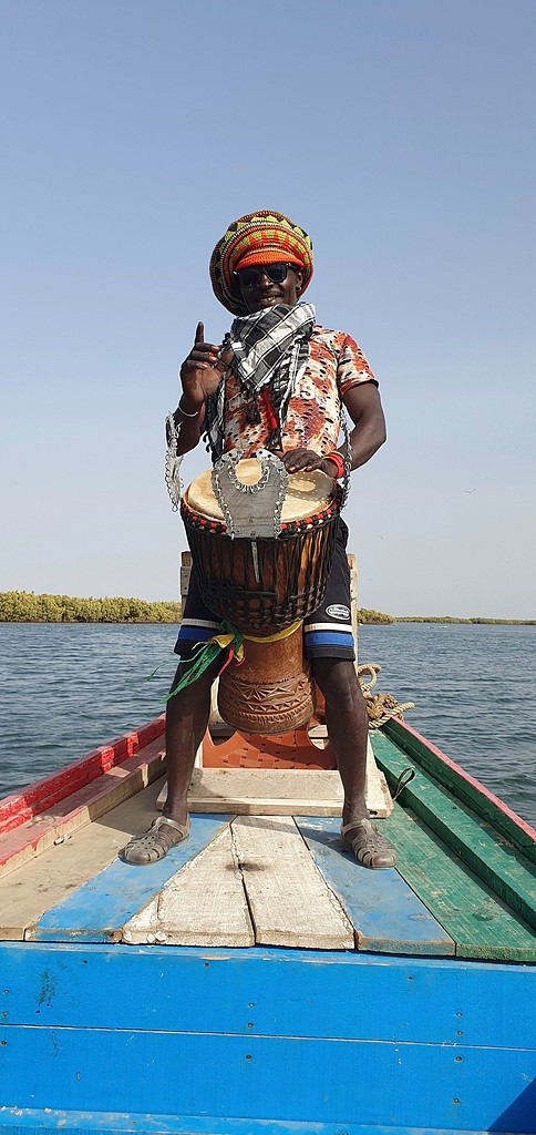 Le joueur de djembé debout à l'avant de la pirogue