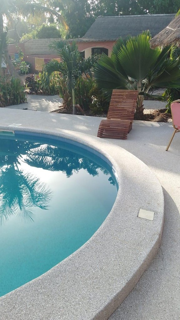Le bord de la piscine et un transat en bois