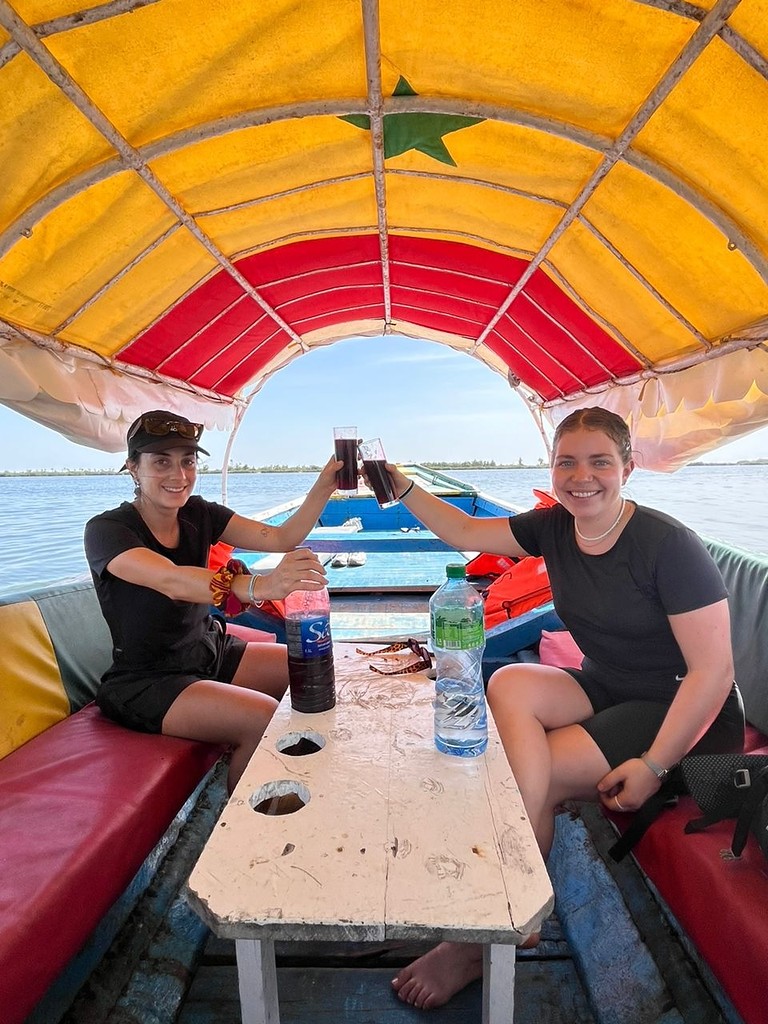 Deux voyageuses trinquent sous le taud de la pirogue